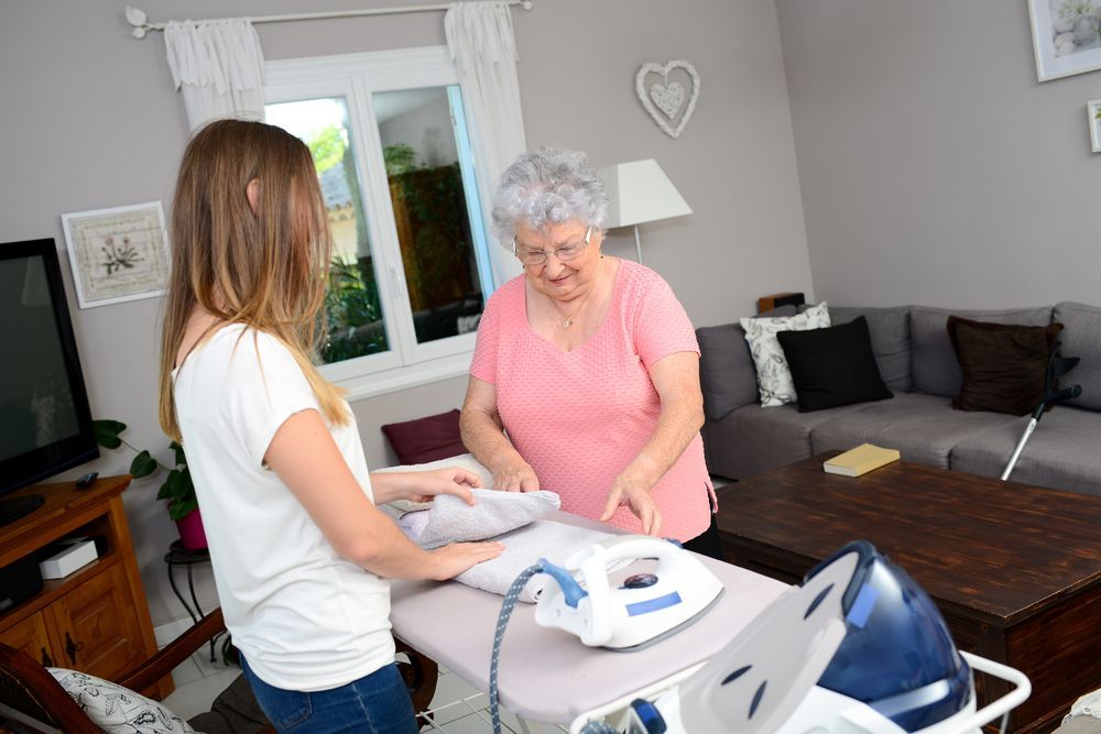 Young Woman and Elderly Woman Ironing Clothes Together in a Living Room — Elder Care Connect in Highland Park, QLD