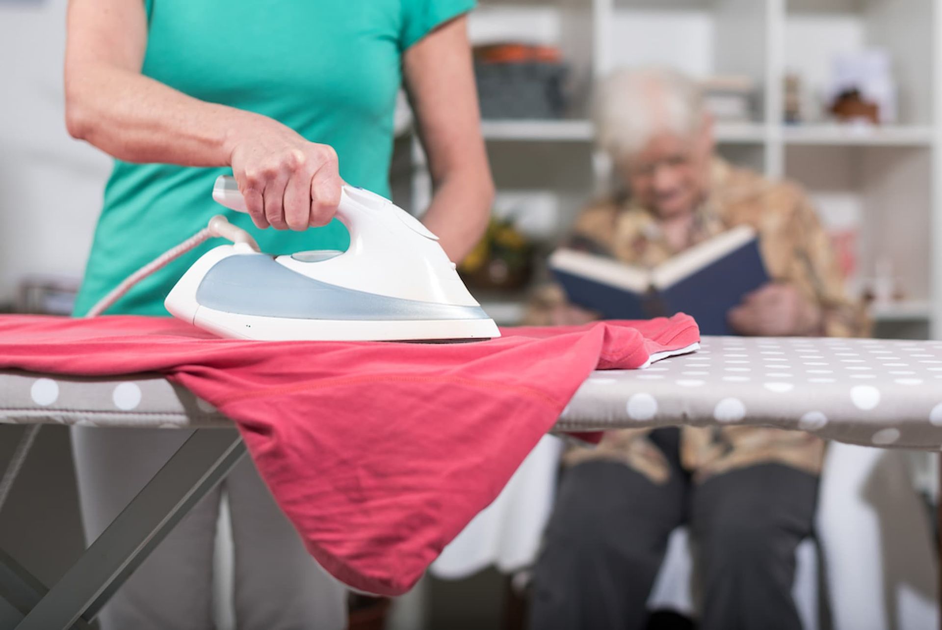 Woman Ironing Red Shirt — Elder Care Connect in Tweed Heads, QLD