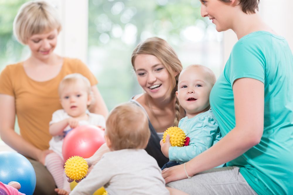 A group of women and babies are playing with balls.