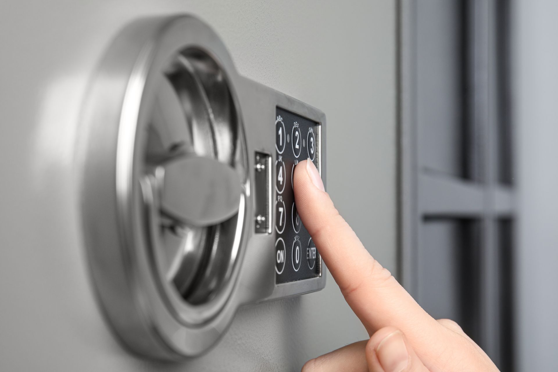 Close-up of a woman confidently opening a steel safe with an electronic lock.