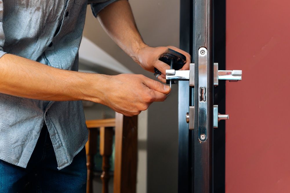 A skilled worker's hands carefully installing a new doorknob and lock.