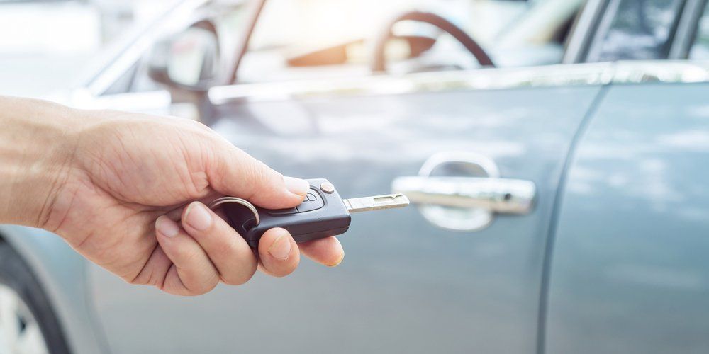 A man using a car key remote to unlock his car.