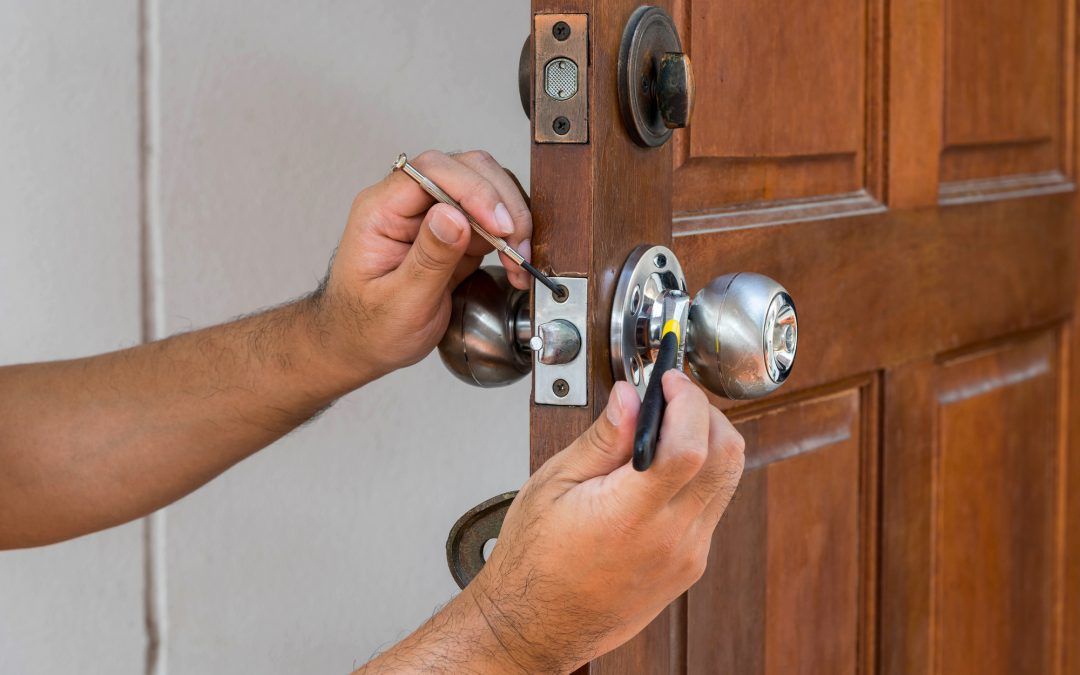 Locksmith repairing a silver doorknob.