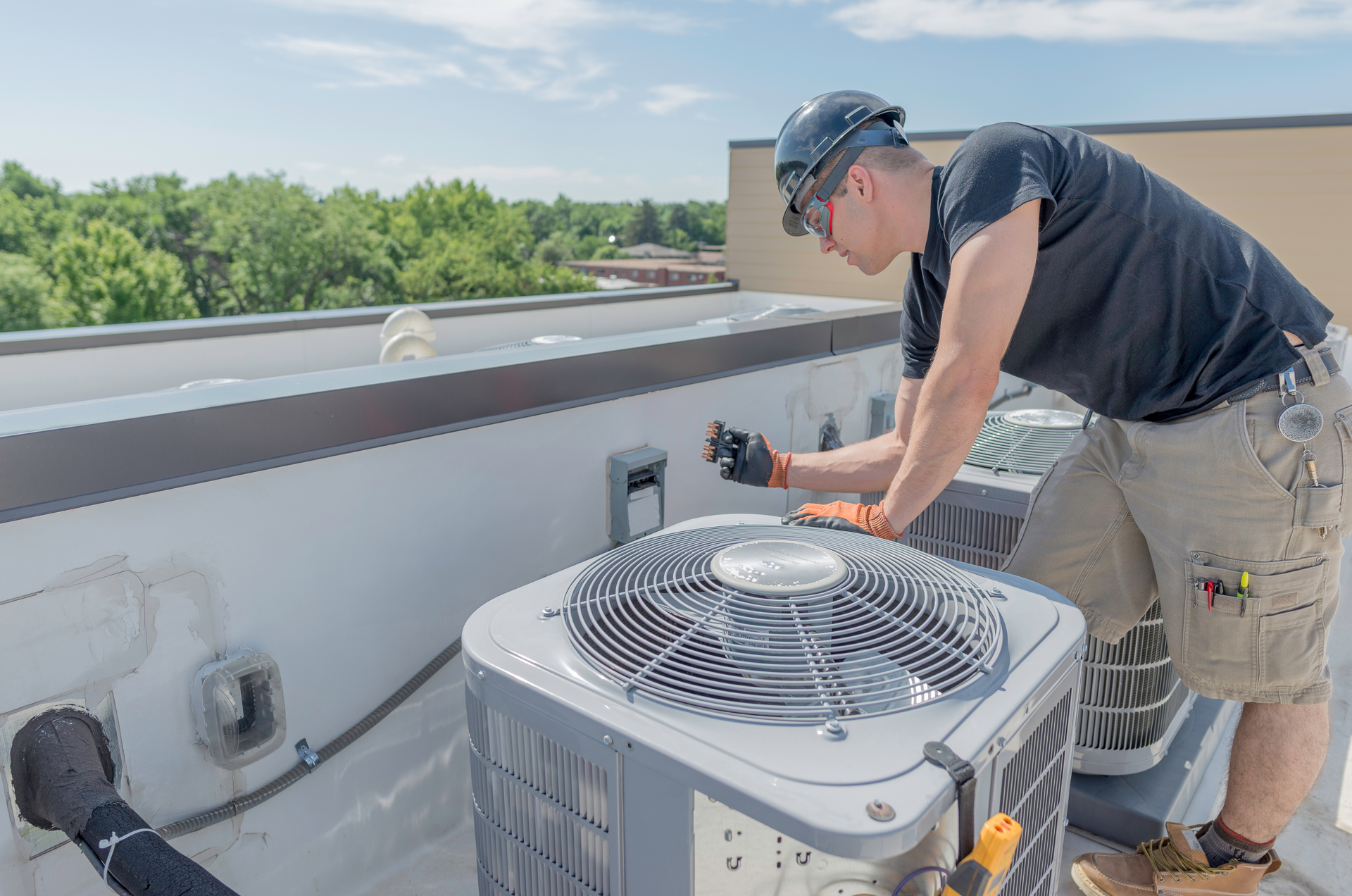 HVAC technician inspecting an air conditioning unit on a rooftop.