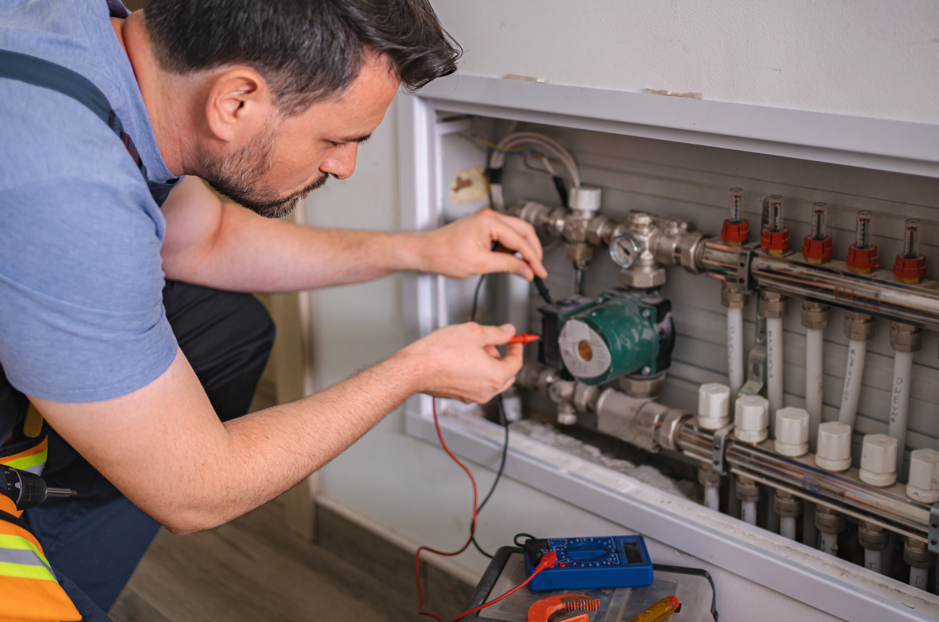 Technician using a multimeter to inspect heating system components.