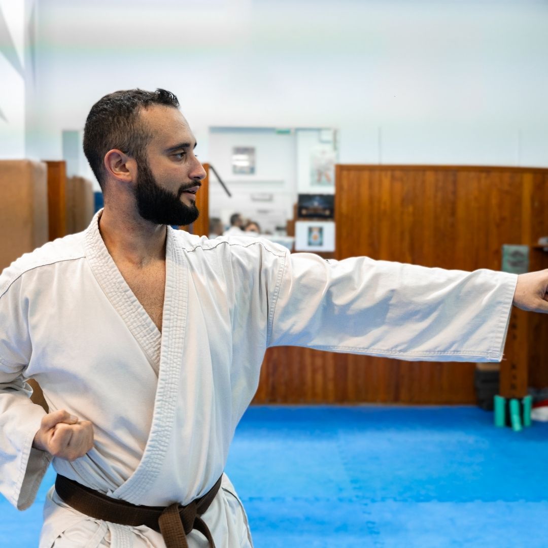 A group of men are practicing karate in a gym.