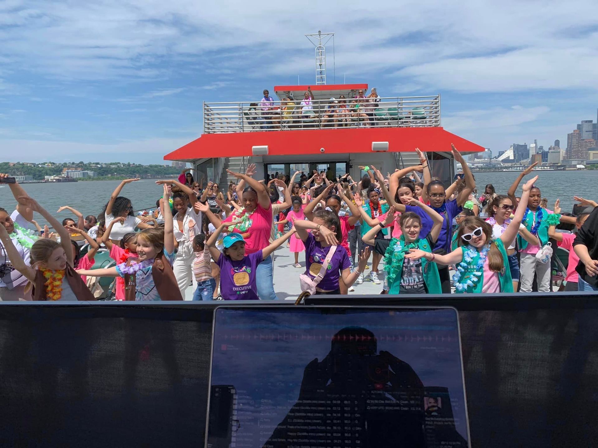 A group of children are dancing on a boat in the water.