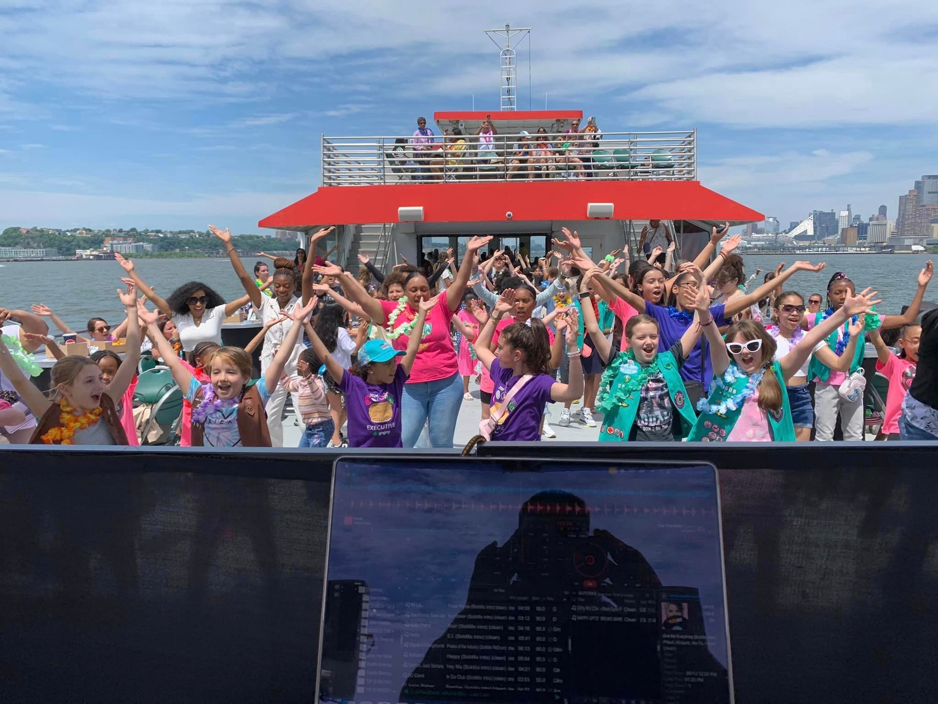 A group of people are standing on a boat with their arms in the air.
