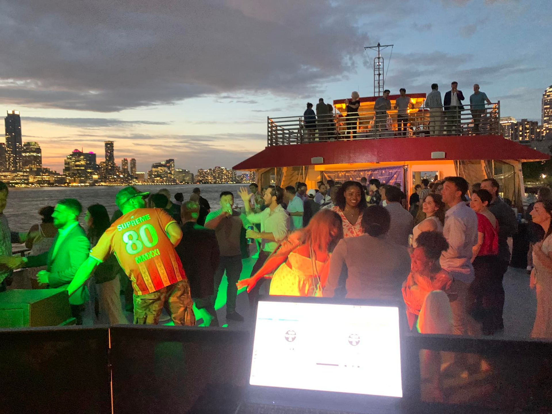 A group of people are dancing on a boat with a man wearing a jersey with the number 80 on it.