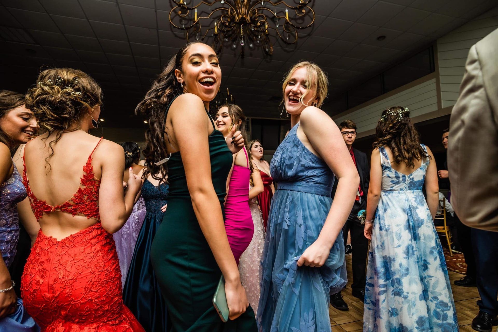 A group of women in dresses are dancing at a prom party.