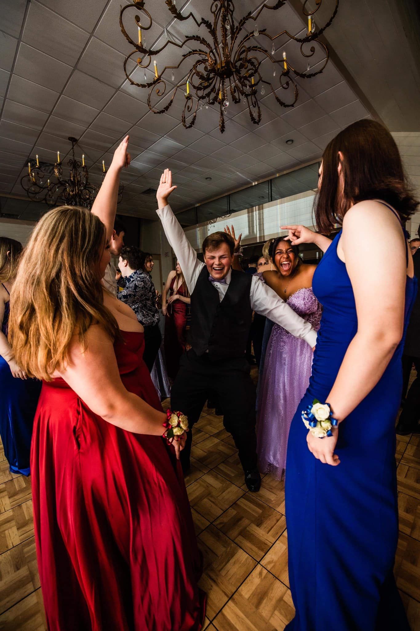 A group of people are dancing in a room at a prom.