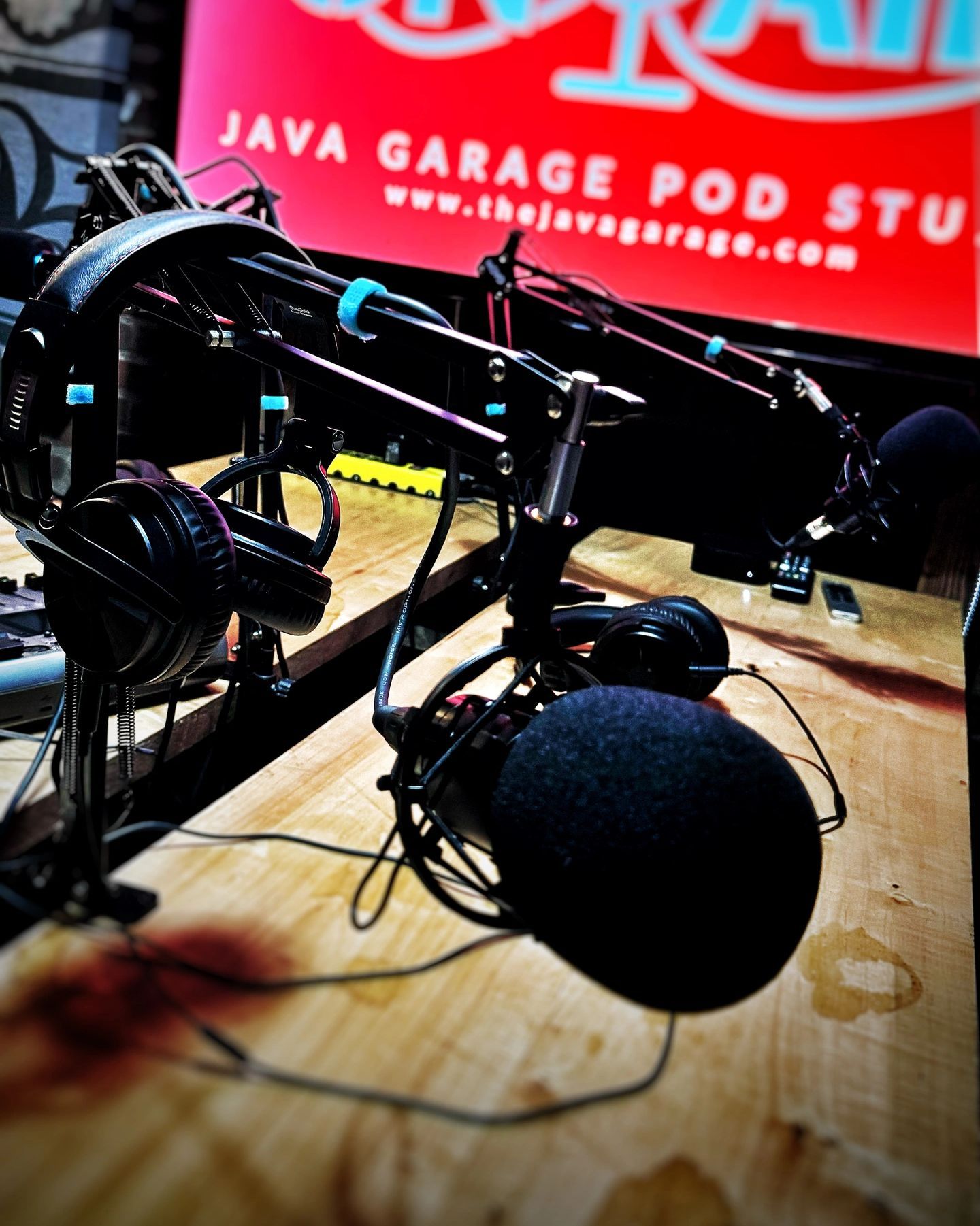 A microphone and headphones in front of a sign that says java garage pod studio