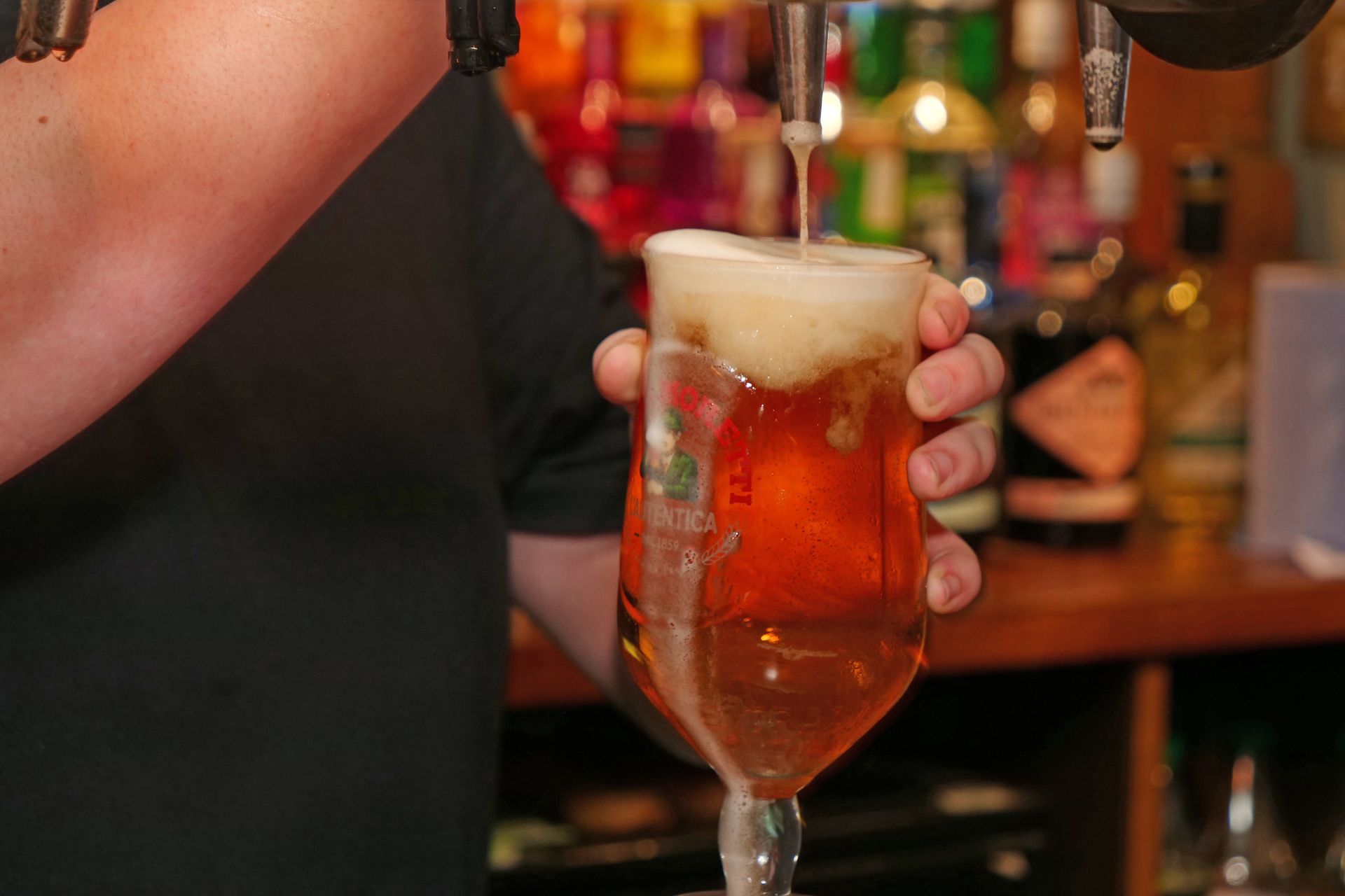 A bartender is pouring beer into a glass at a bar.