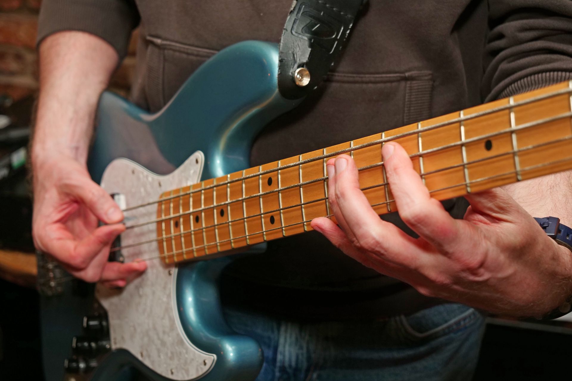 A man is playing a blue electric bass guitar