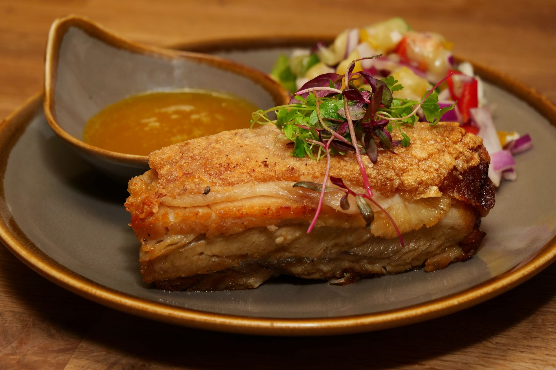 A plate of food with meat and vegetables on a wooden table.