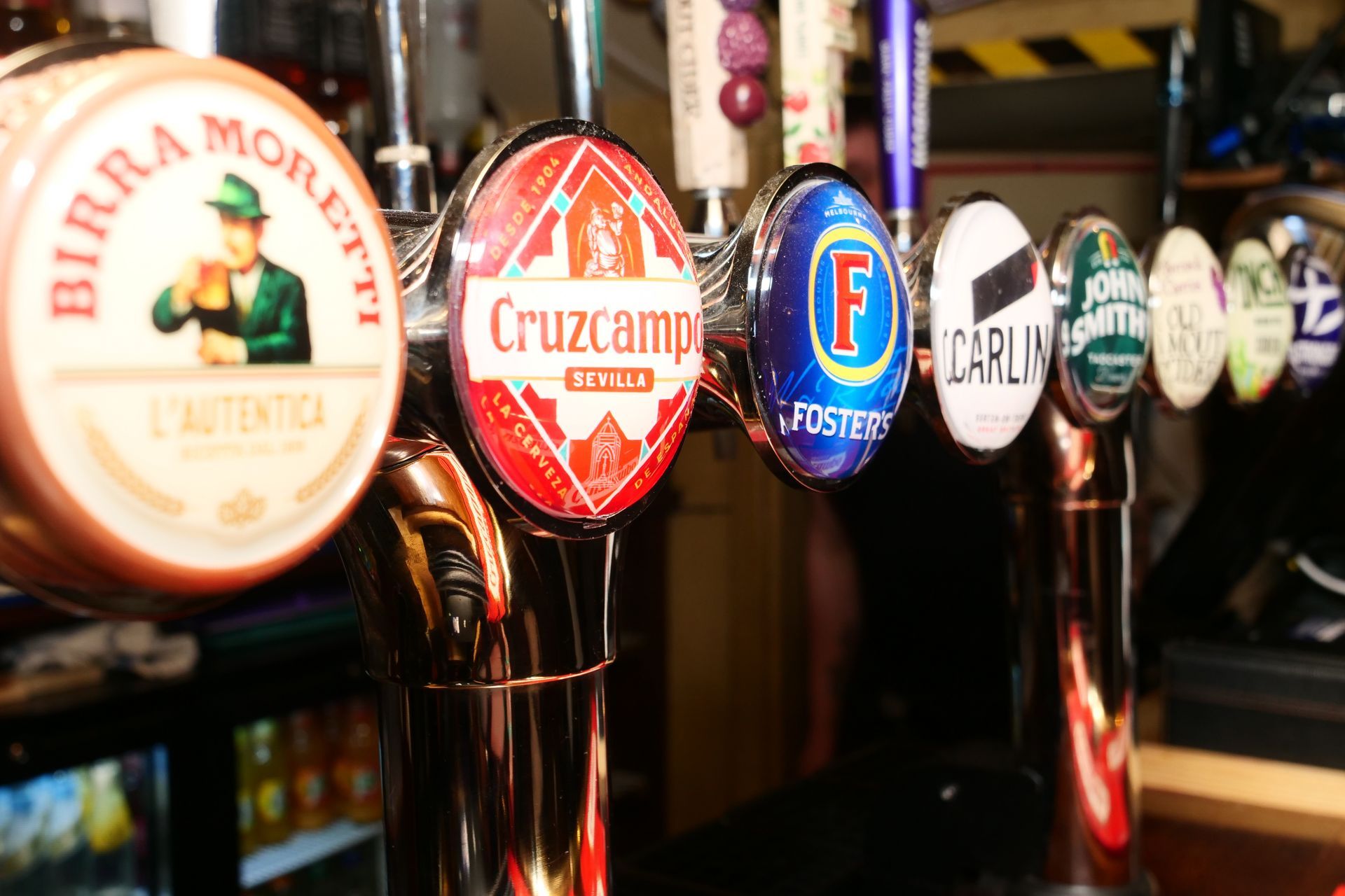 A row of beer taps with one that says cruzcampo on it
