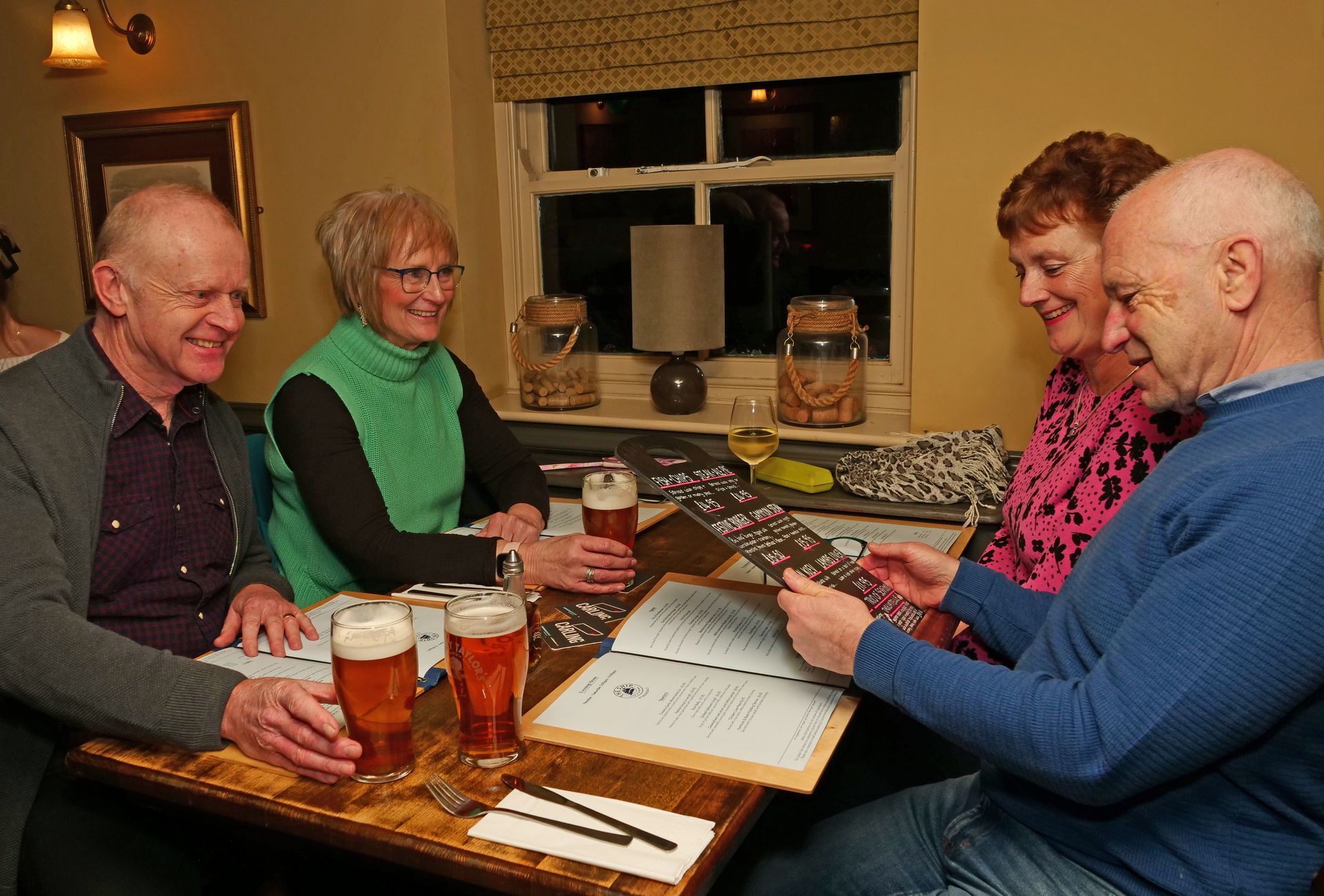 A group of people are sitting at a table looking at a menu