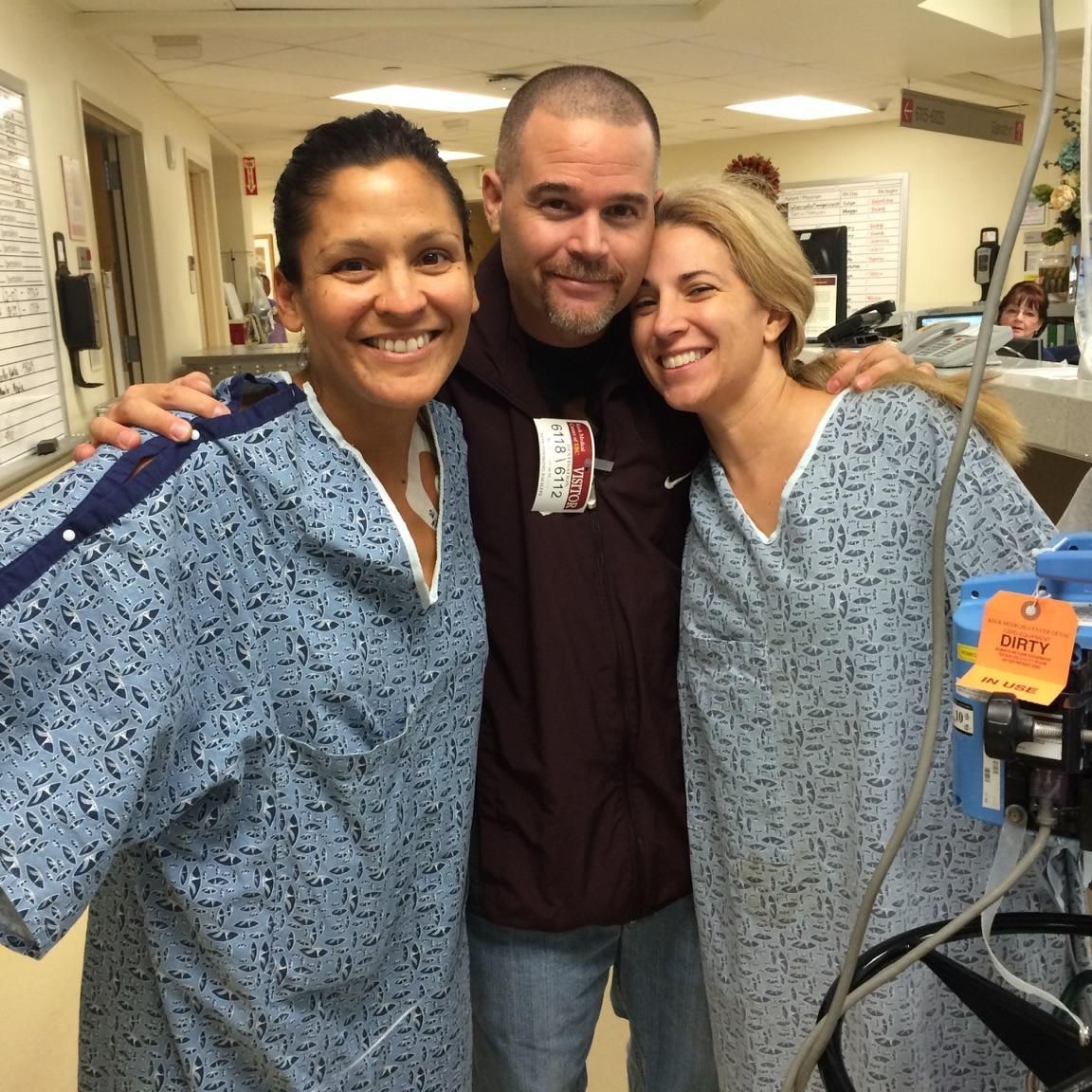 A man and two women are posing for a picture in a hospital room