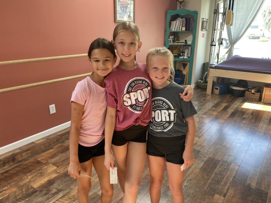 three young girls are posing for a picture in a dance studio .