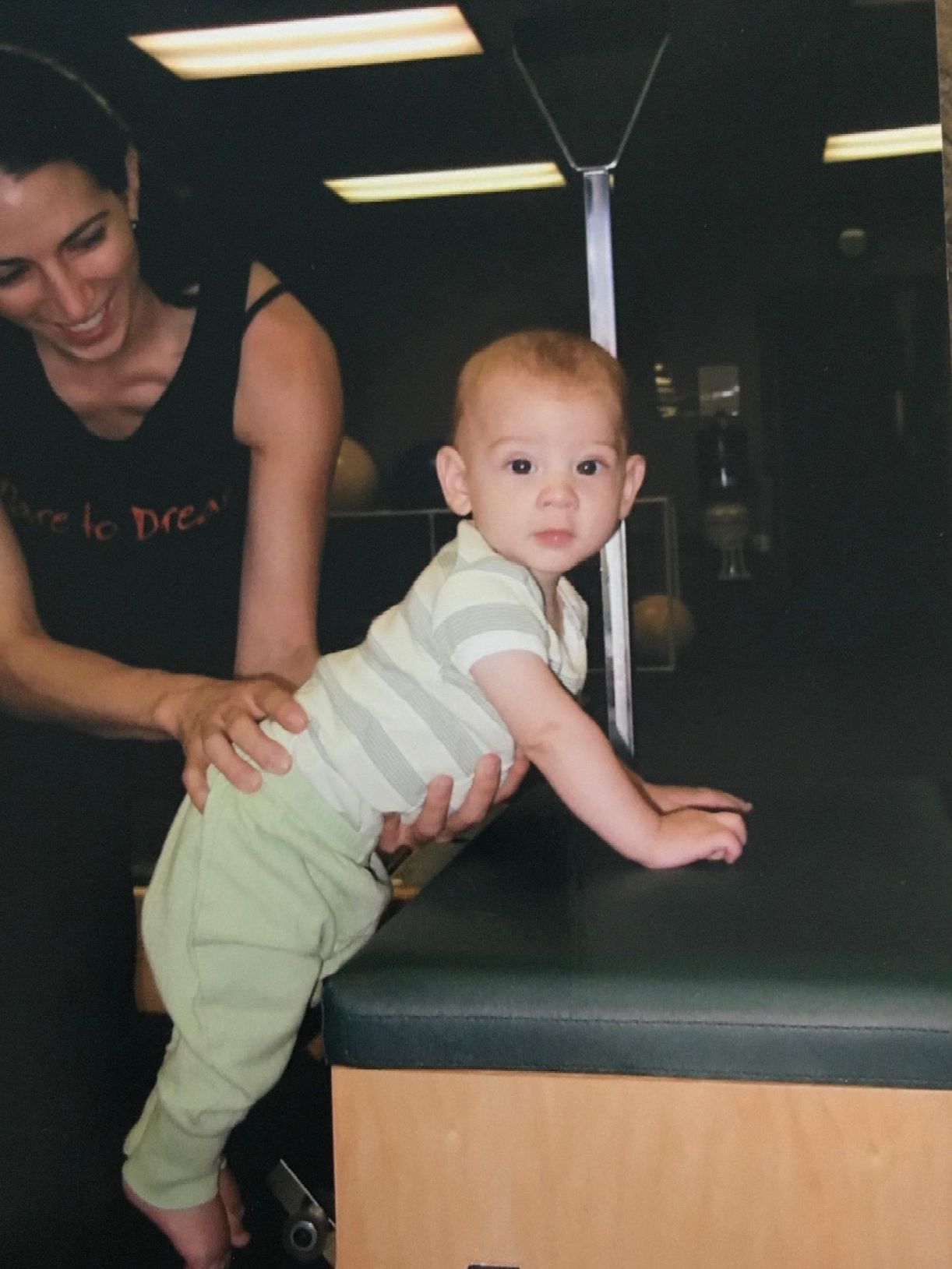 a woman is holding a baby who is crawling on a table