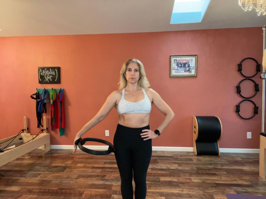 a woman is standing in a room holding a pilates ring .