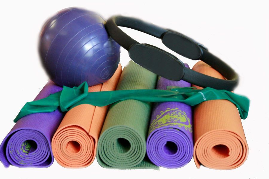 A stack of yoga mats a pilates ball and a ring