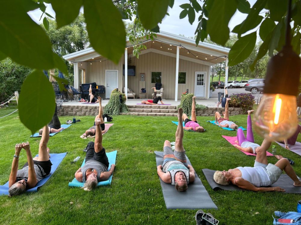 A group of people are doing yoga in the grass in front of a building.