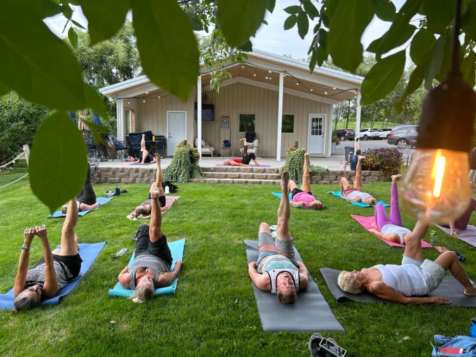 a group of people are doing Pilates in the grass in front of a building .