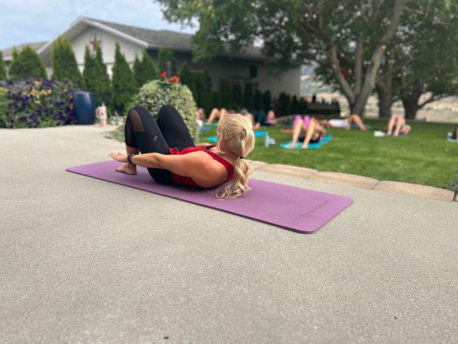 a woman is laying on a purple yoga mat in front of a house .