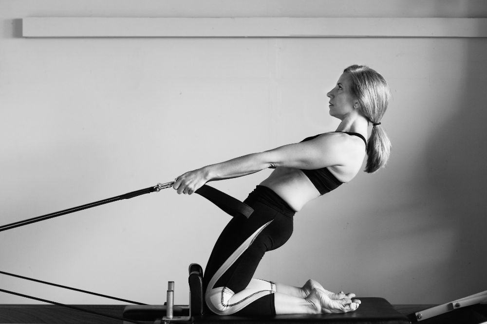 A woman is doing pilates on a pilates machine in a black and white photo.