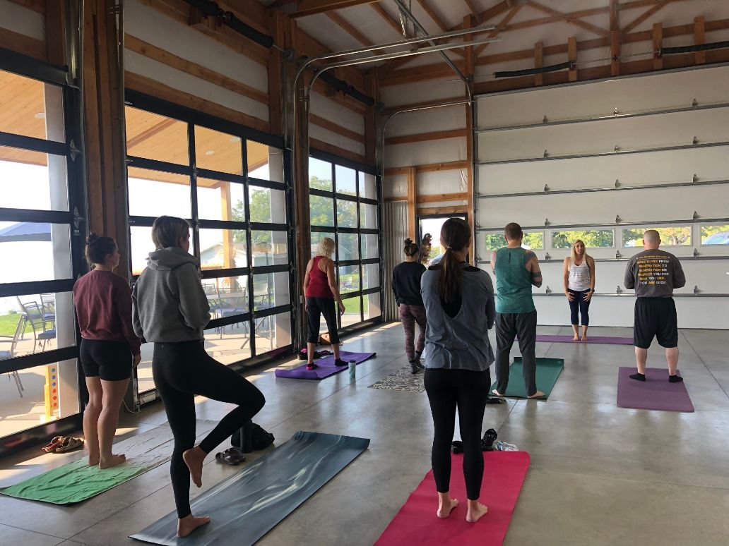 a group of people are standing on Pilates mats in a room .
