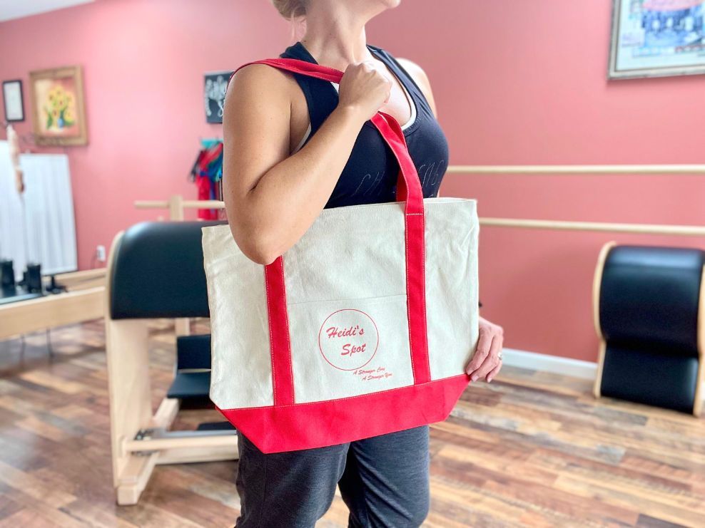 a woman is holding a red and white tote bag in a gym .