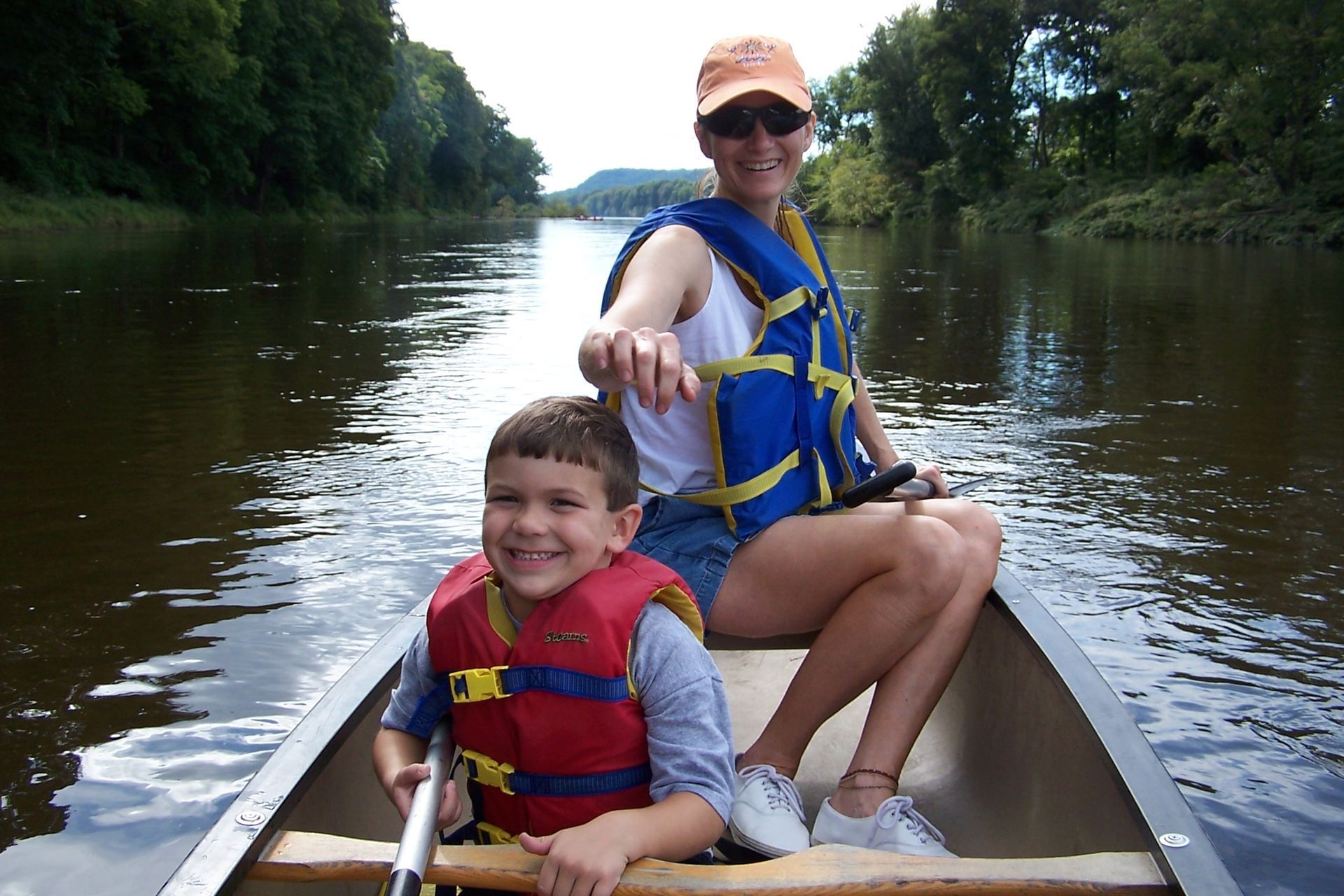 A woman and a boy are in an adventure sports canoe on a river