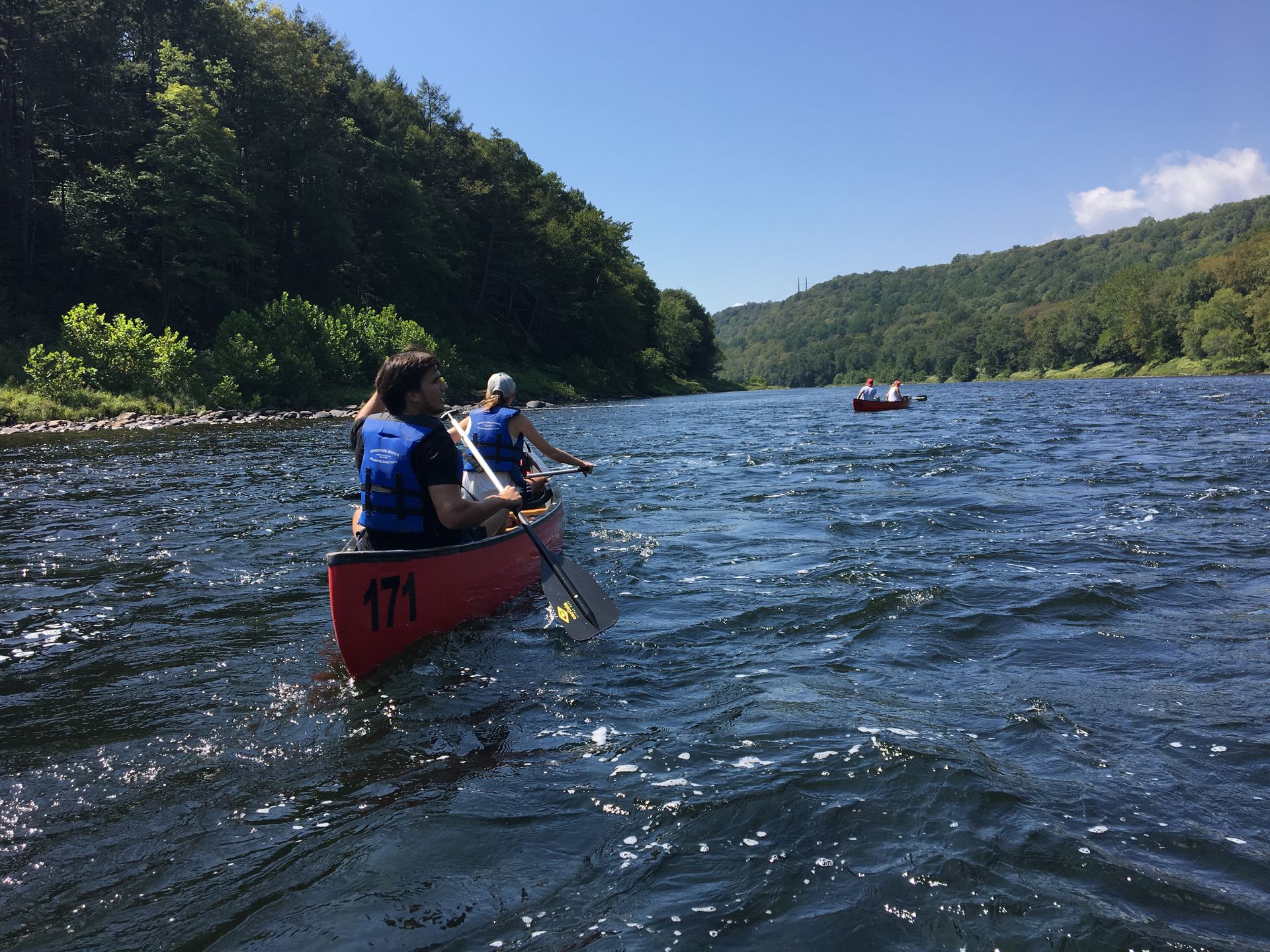 Two people are in a red adventure sports canoe on a river.