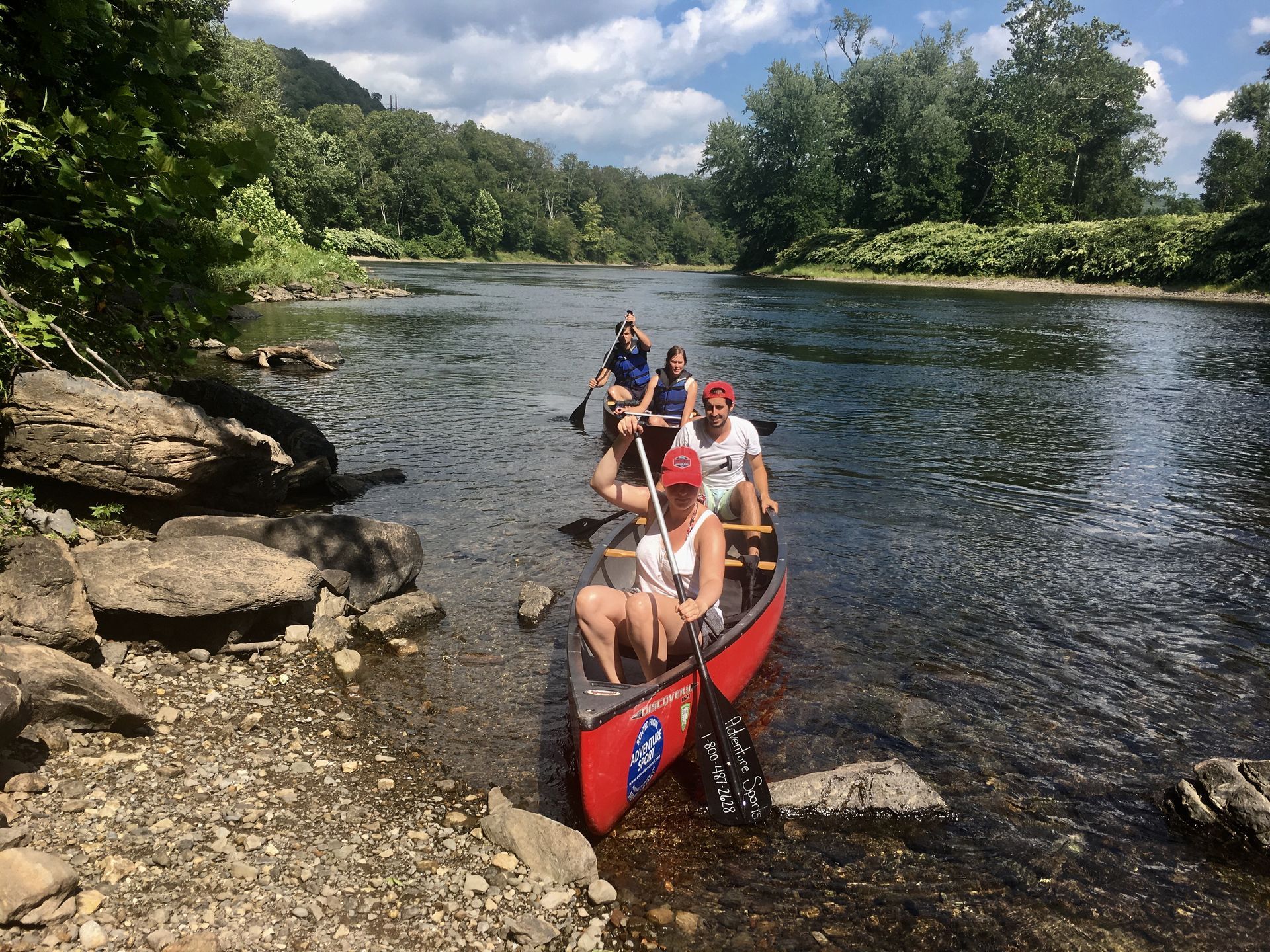 A group of people are in an adventure sports canoe on a river.