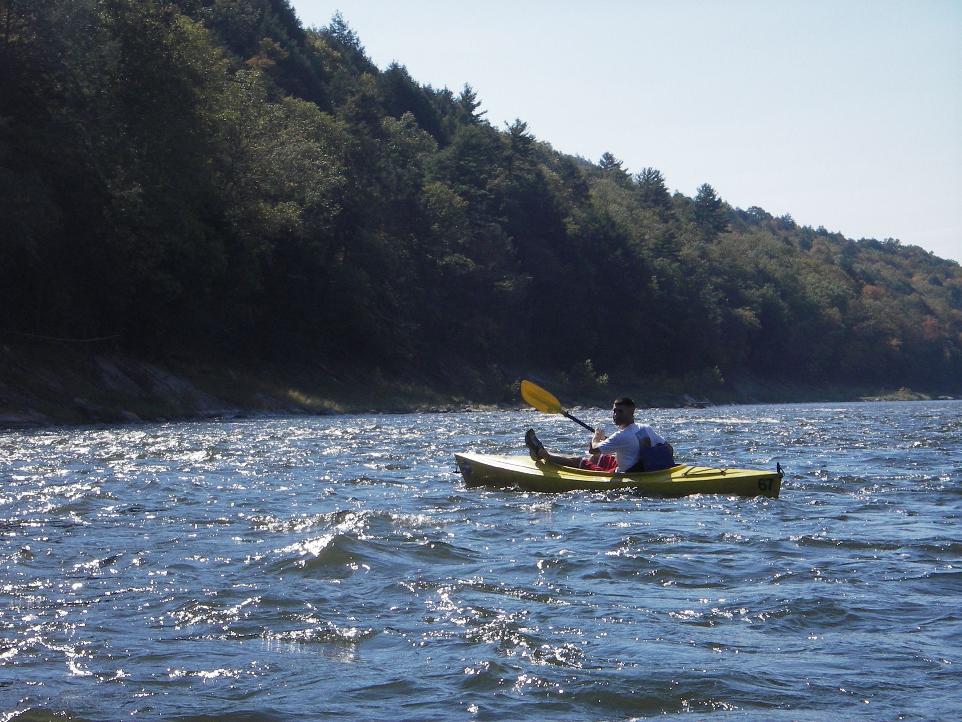 A man in a yellow kayak is paddling down a river
