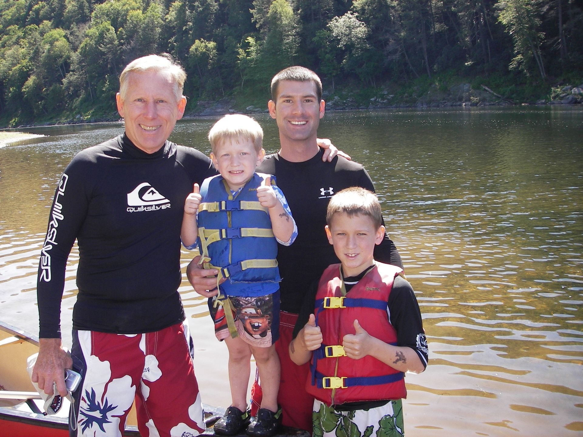A man wearing a quiksilver shirt is standing next to two boys  at adventure sports