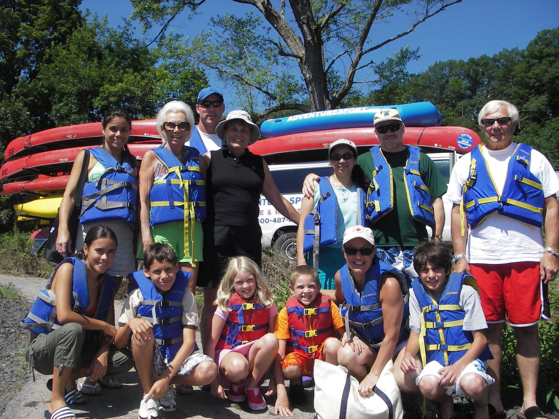 A group of people wearing life jackets pose for a picture after an adventure sports trip