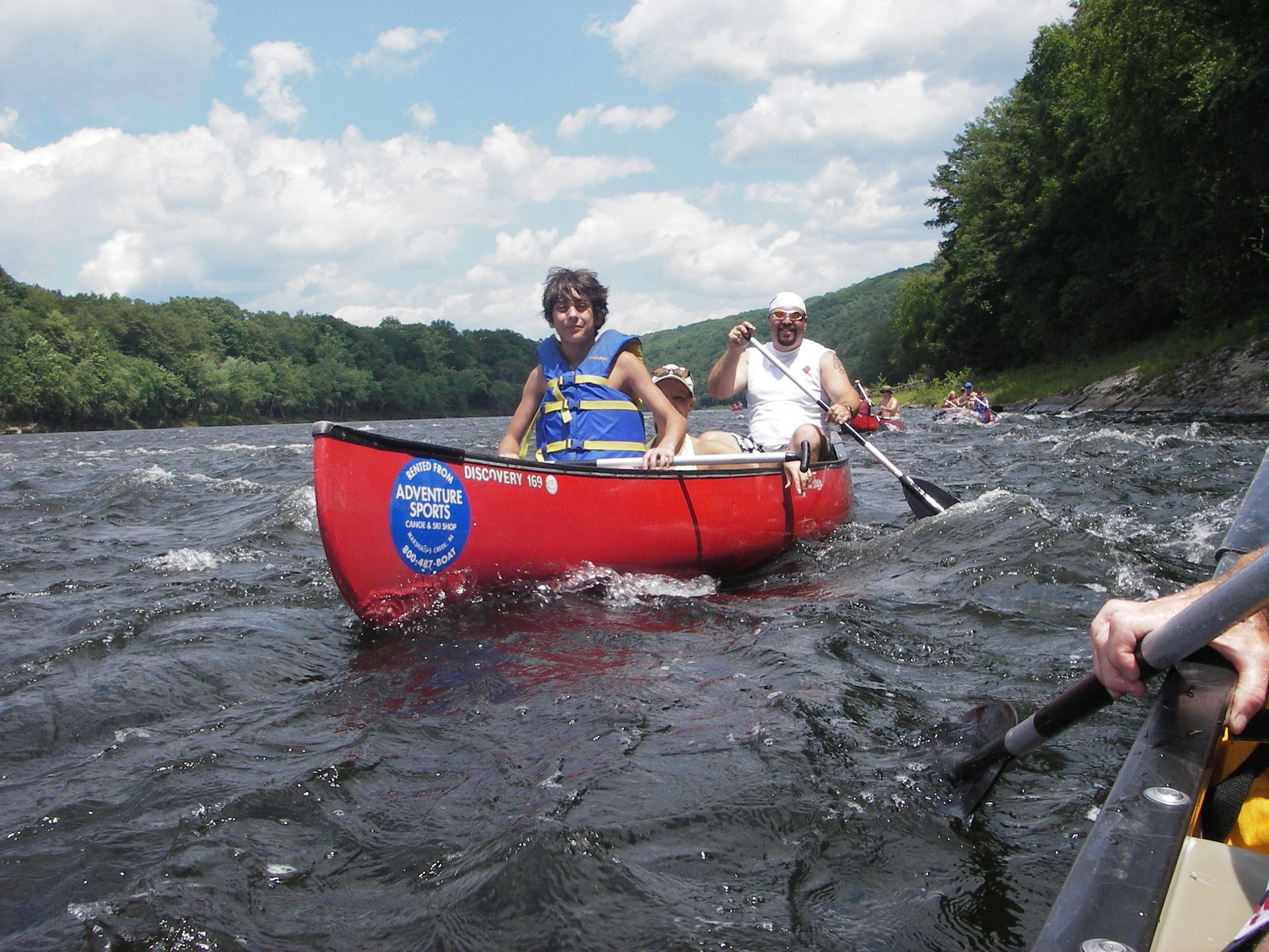 Two people in a red adventure sports canoe with a blue sticker on the side