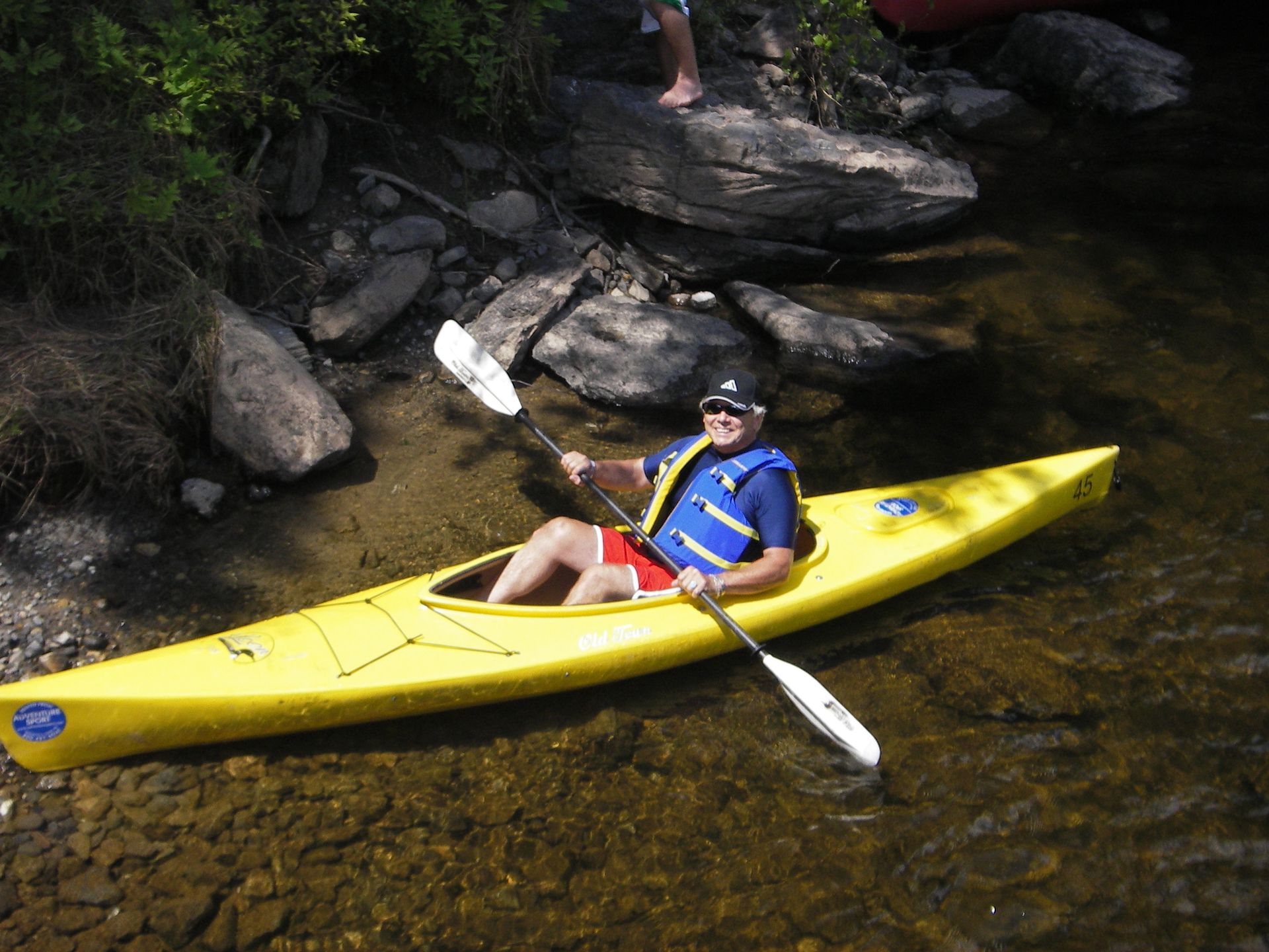 A man is paddling a yellow adventure sports kayak in a river