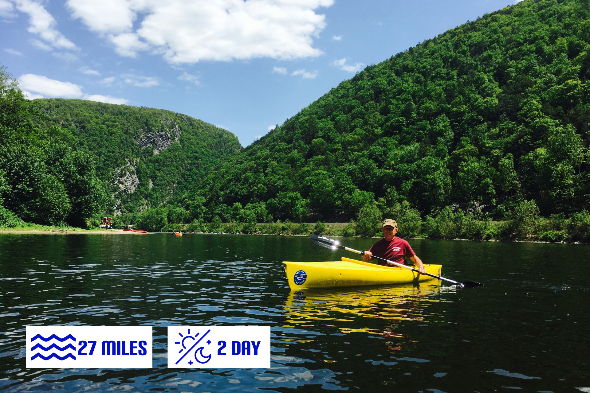 A man in a yellow kayak on a lake with mountains in the background