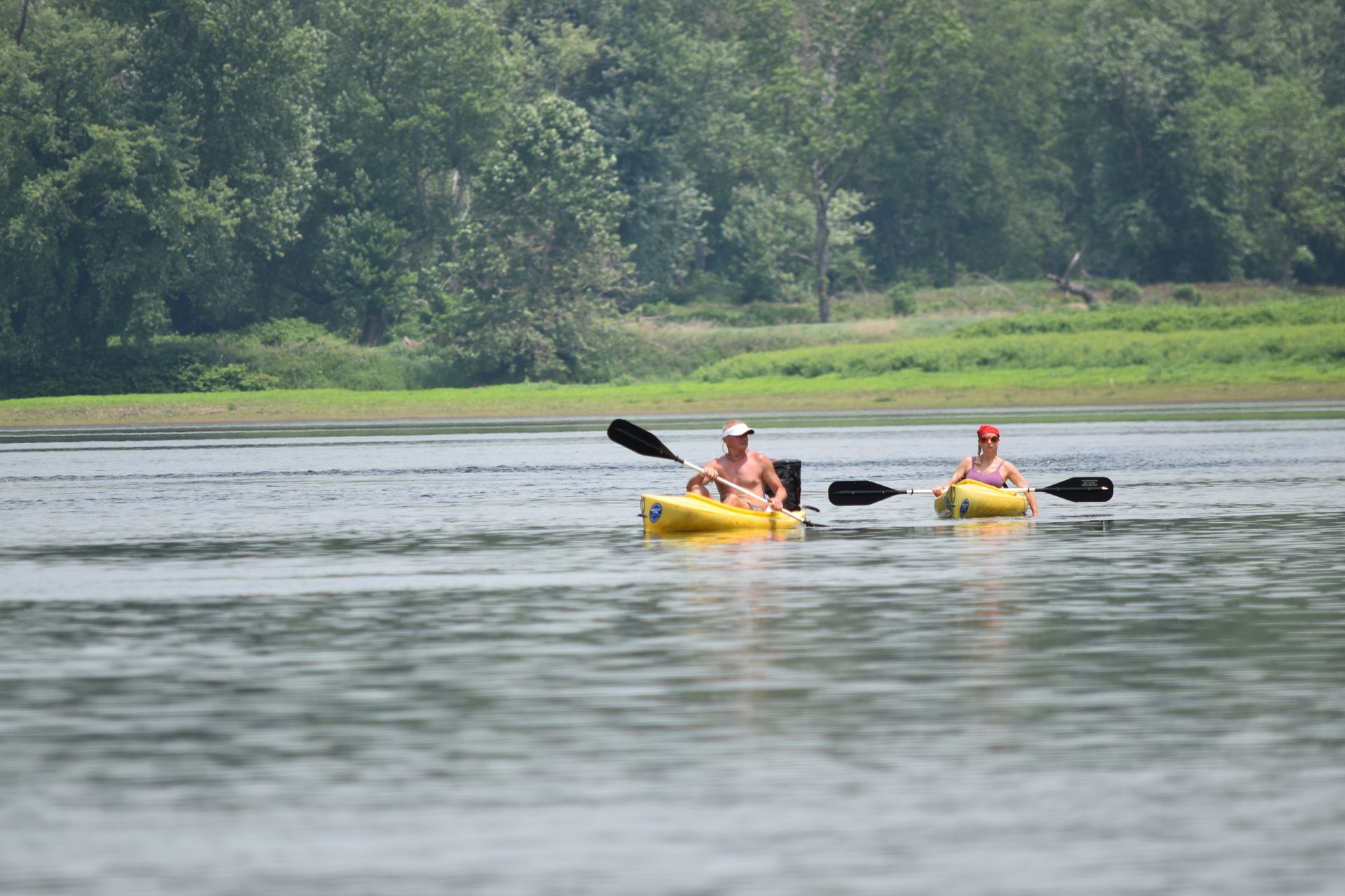 Two people are paddling kayaks on a lake.
