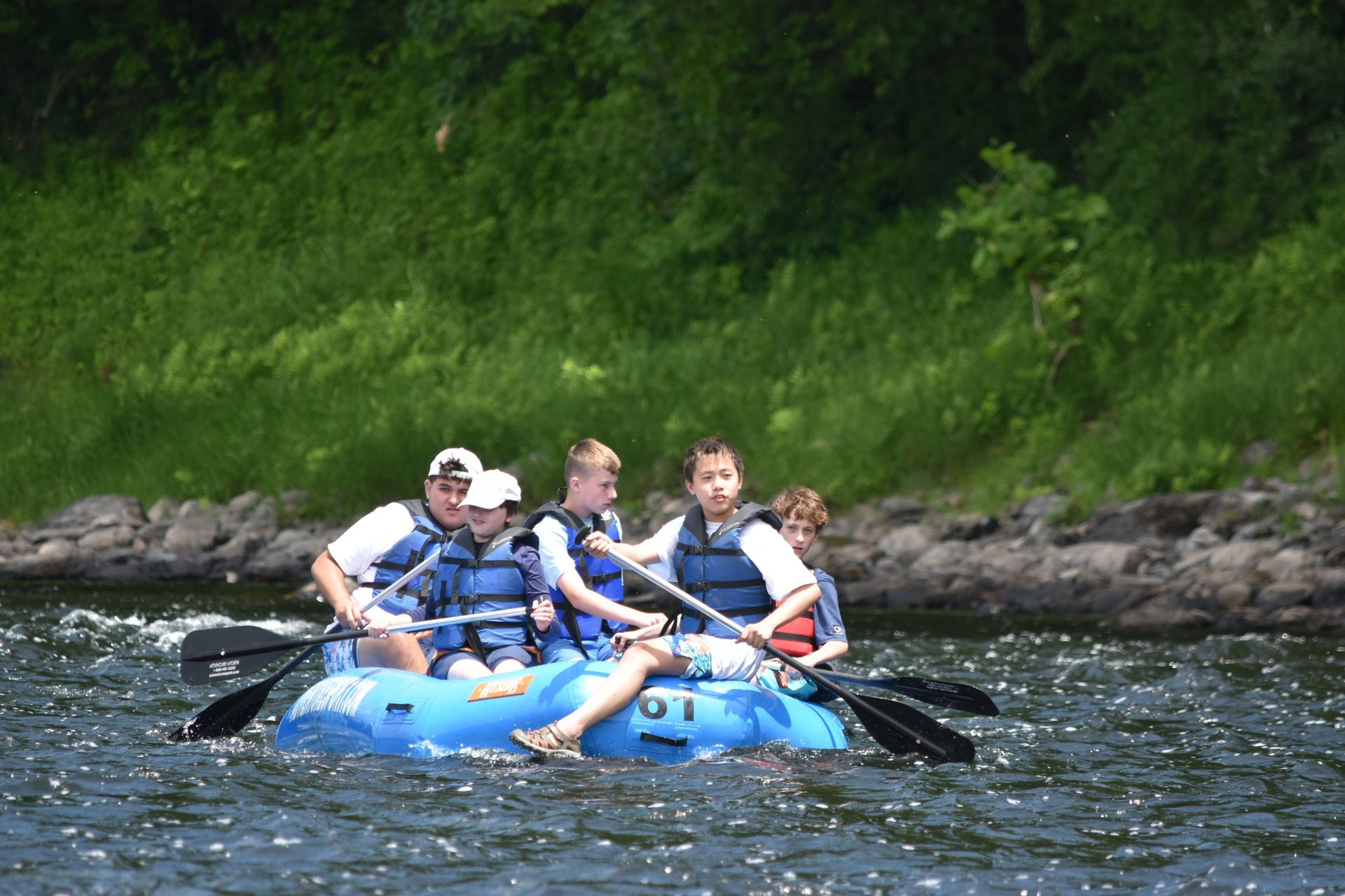 A group of people are rowing an adventure sports raft down a river.
