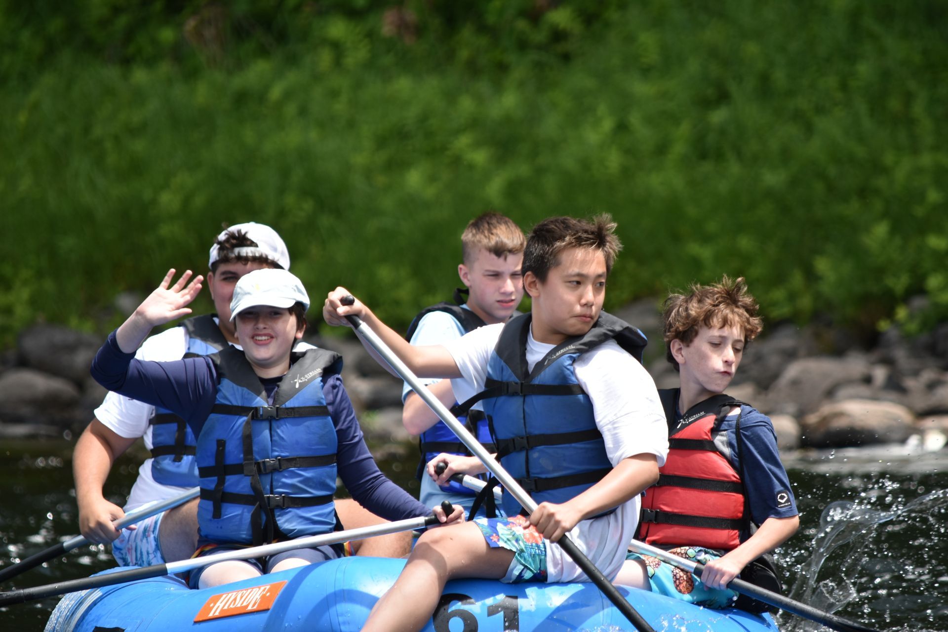 A group of people are rowing an adventure sports raft down a river.