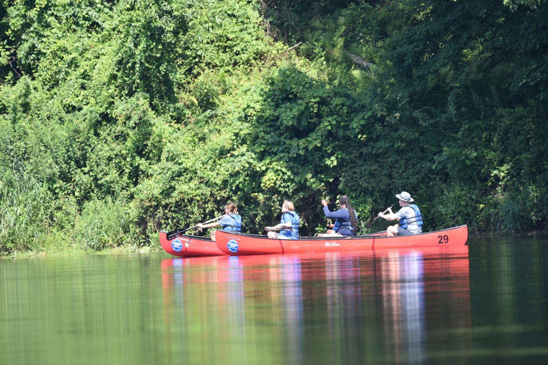 A group of people are in a red adventure sports canoe on a lake.