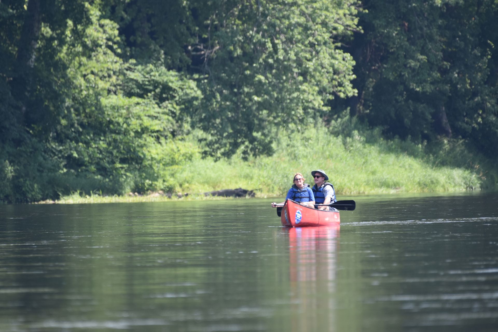 Two people are in a red adventure sports kayak on a river.