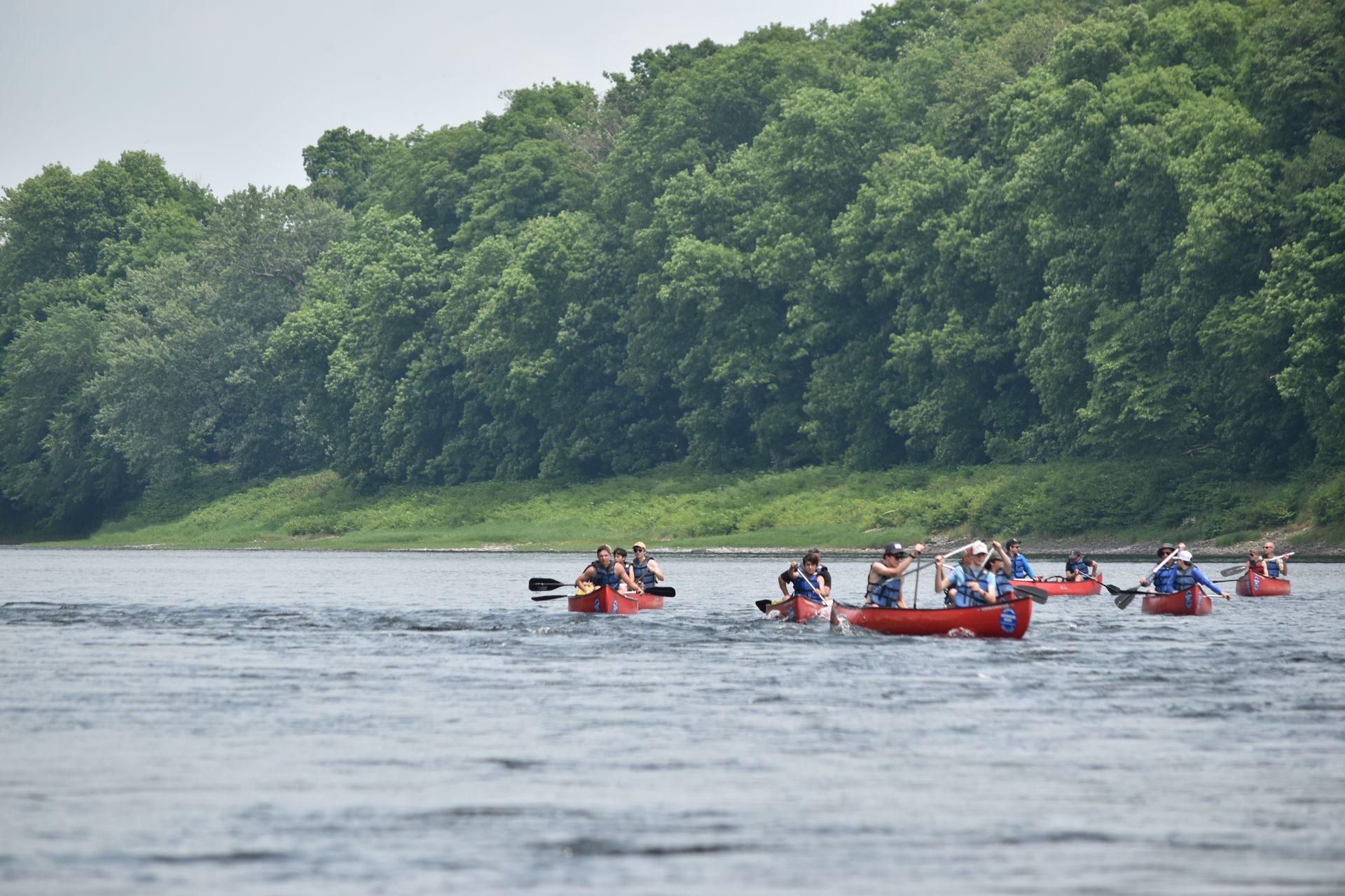 A group of people are rowing adventure sports kayaks down a river.