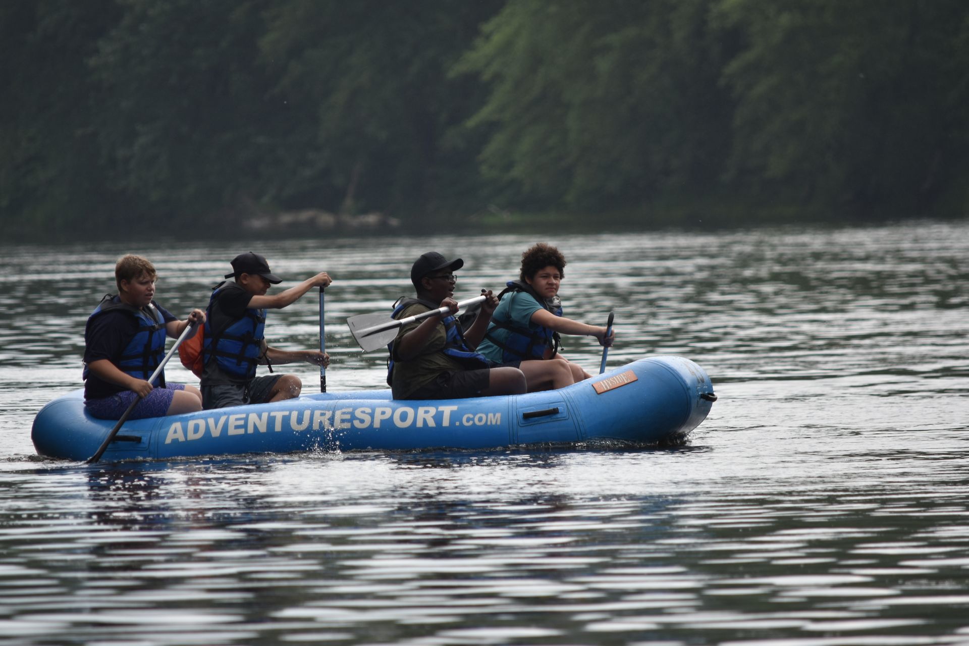 A group of people are rowing an adventure sports raft on a lake.