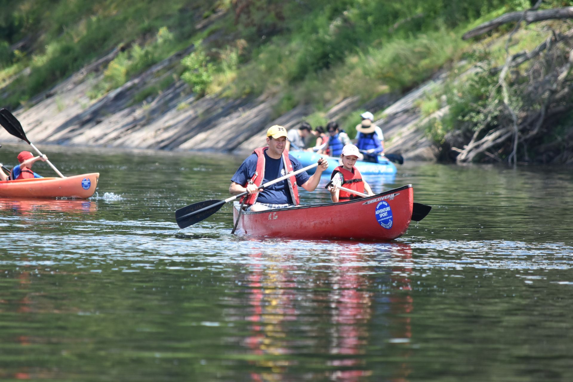 A group of people are rowing adventure sports kayaks down a river.