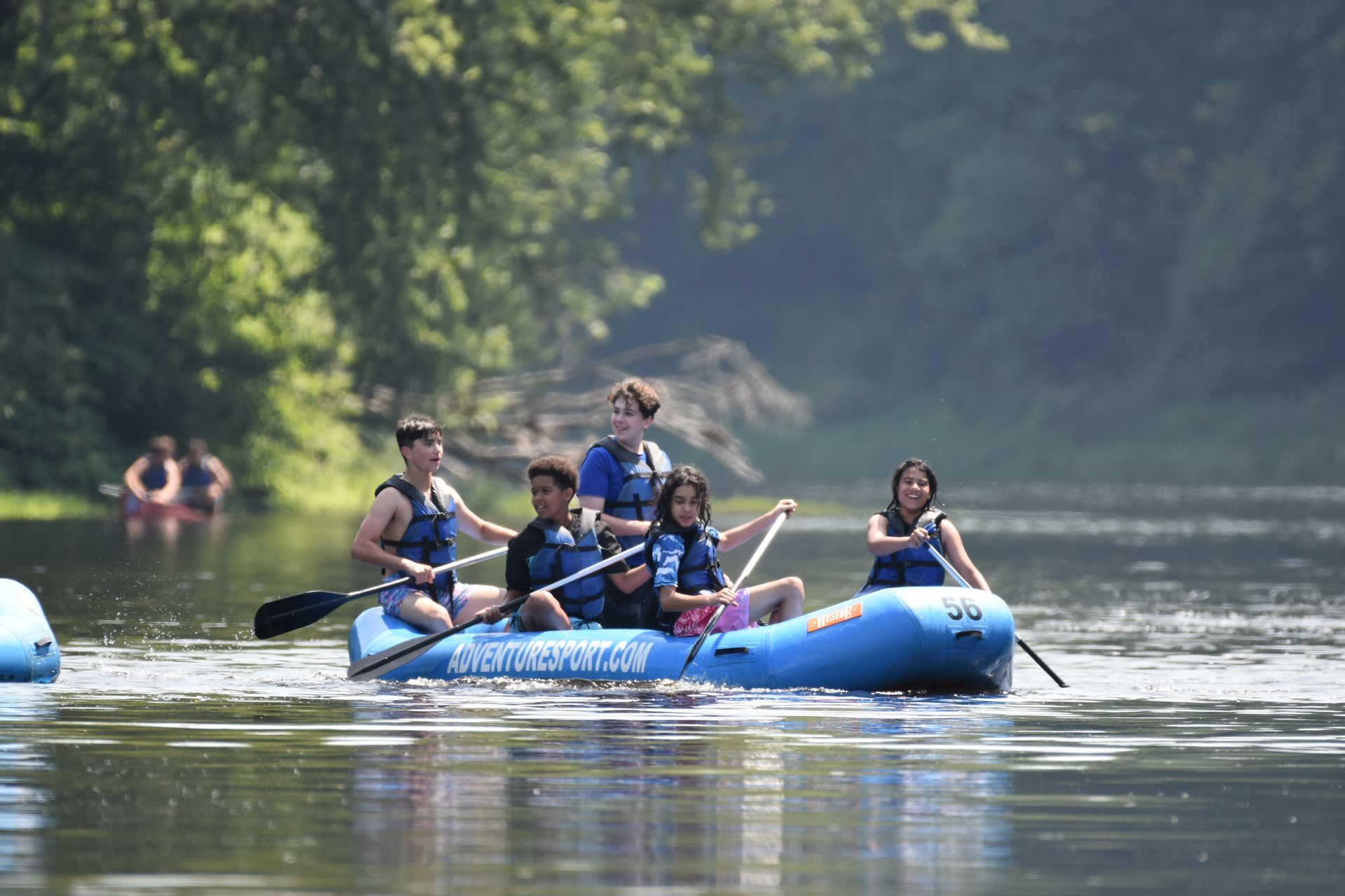 A group of people are rowing an adventure sports raft down a river.